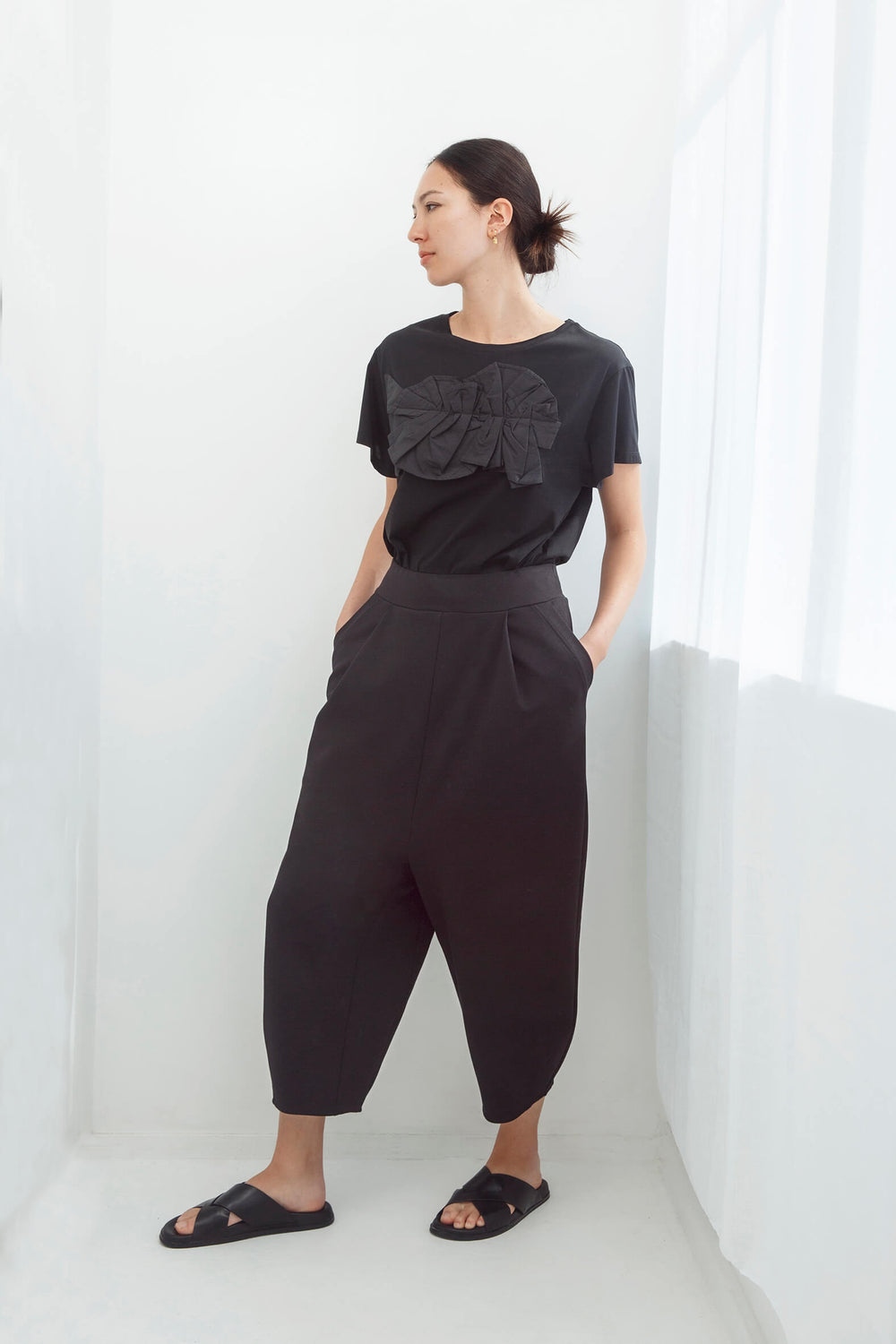 Woman wearing an original handmade black top and japanese pants against a white background