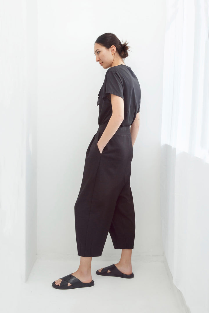 Woman wearing an original handmade black top and japanese pants against a white background