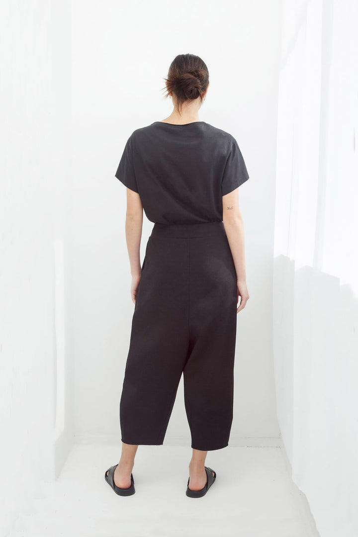 Woman wearing an original handmade black top and japanese pants against a white background