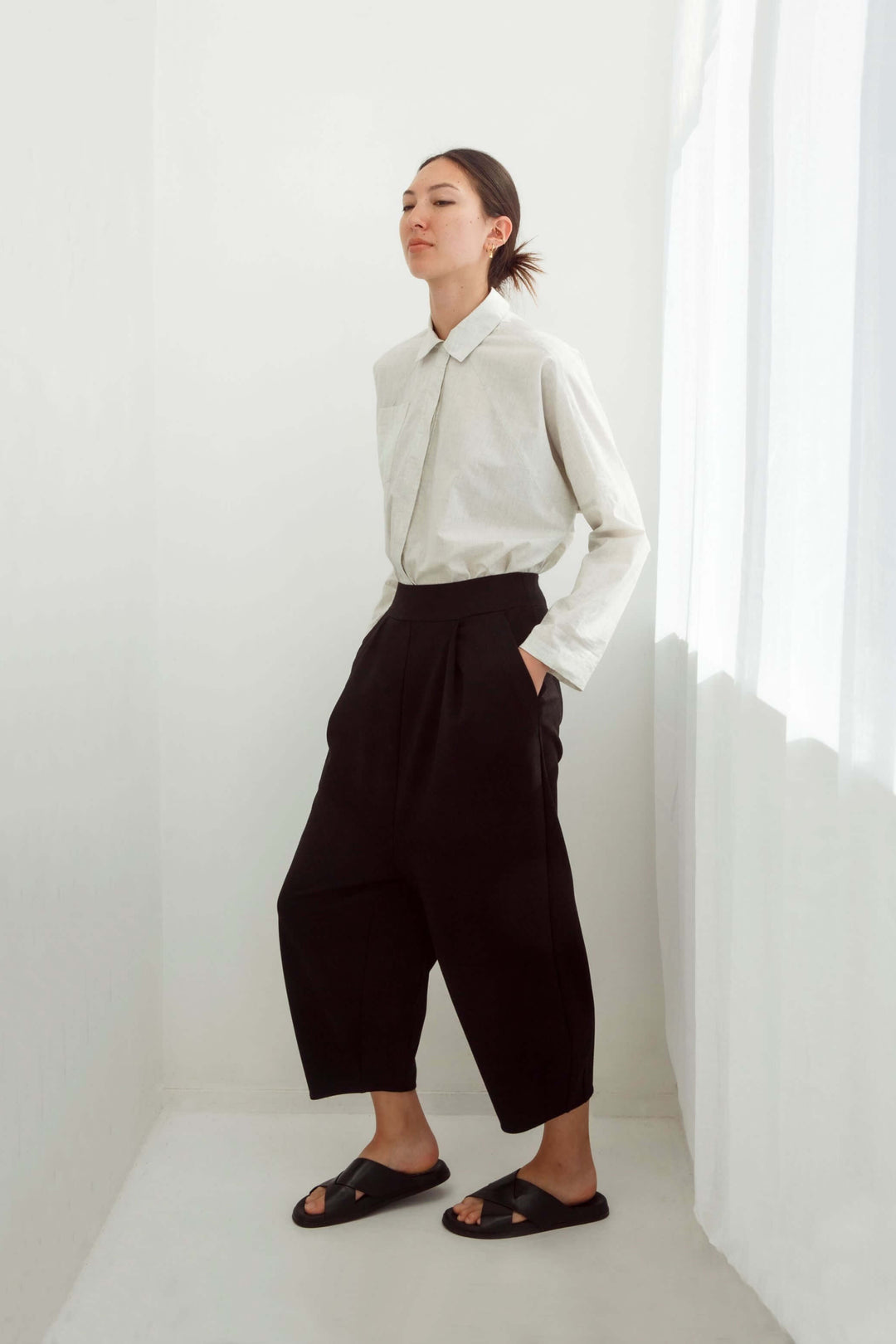 Woman wearing an original beige shirt and japanese pants against a white background