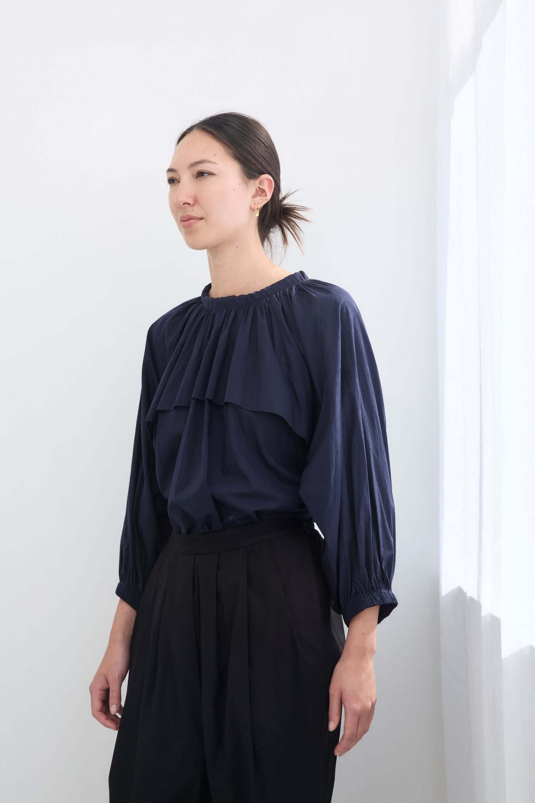 woman wearing a romantic, feminine,  navy, handmade, gathered frilled, puffed sleeve, pussy bow cotton top