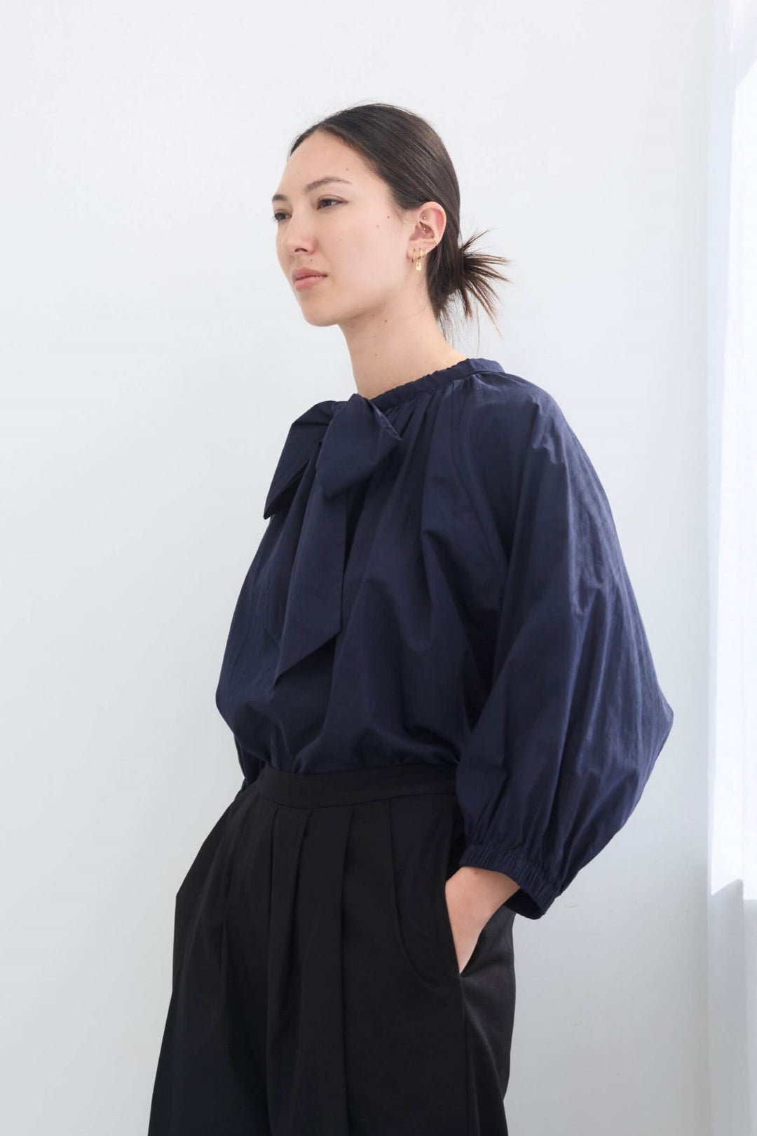 woman wearing a romantic, feminine,  navy, handmade, gathered frilled, puffed sleeve, pussy bow cotton top